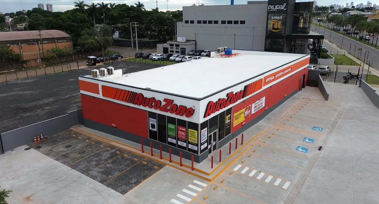 Vista aérea de drone da loja Autozone em Goiânia, pronta, com fachada vermelha e branca, letreiros da marca e estacionamento sinalizado