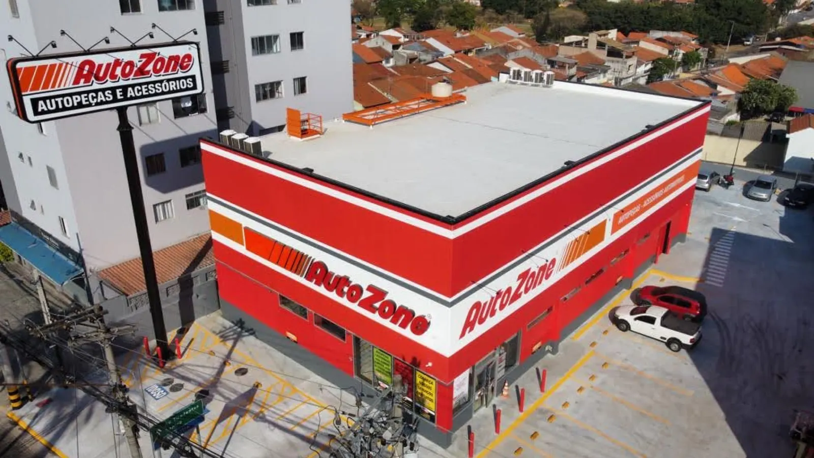 Vista aérea da loja Autozone em Guarulhos, prédio vermelho com letreiros e totem Autopeças e Acessórios na esquina