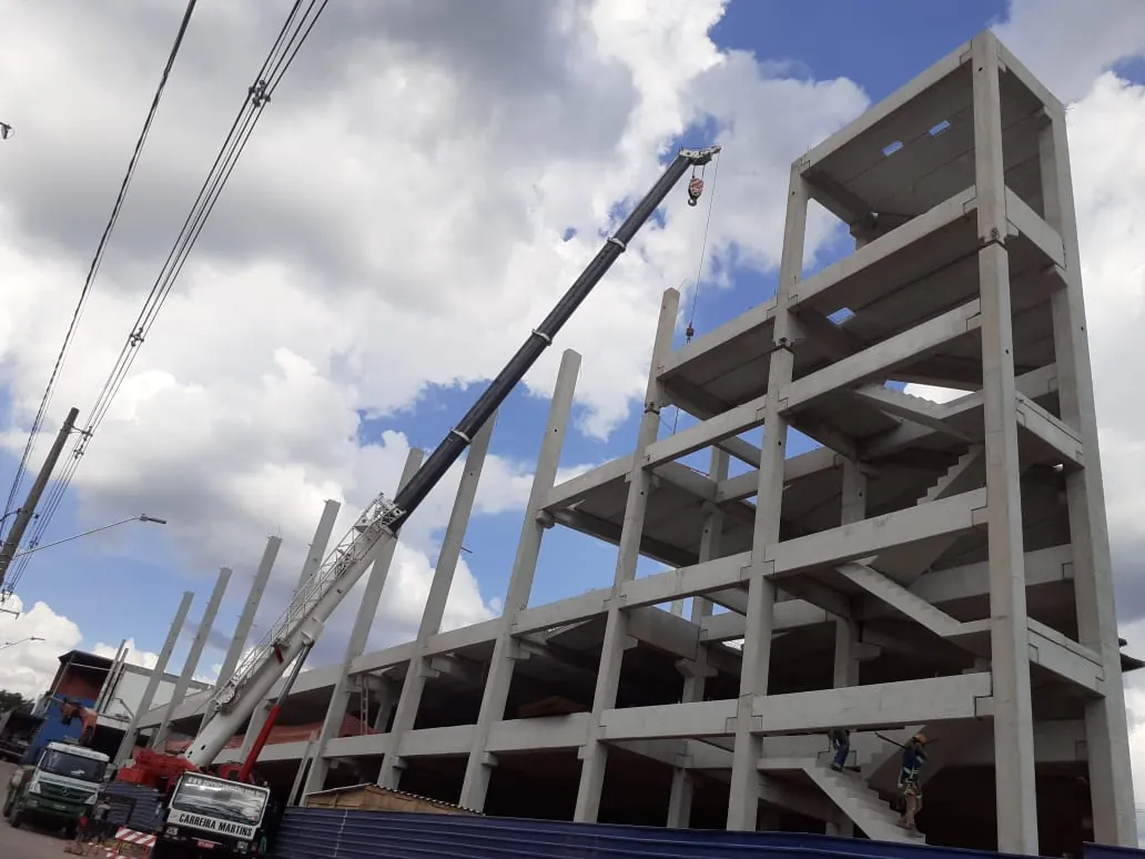 Estrutura de concreto do Mercadão Atacadista em Cotia durante a montagem, com vários pavimentos, pilares e lajes e guindaste