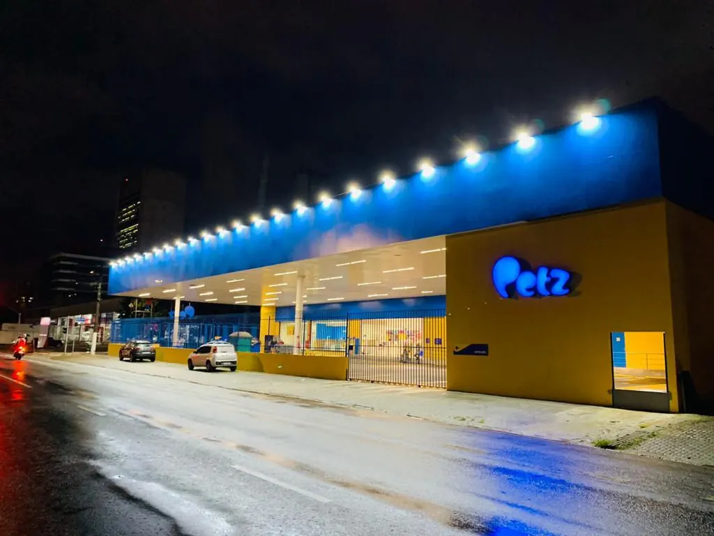 Fachada noturna da loja Petz Gastão Vidigal com marquise azul iluminada e letreiro Petz em parede amarela