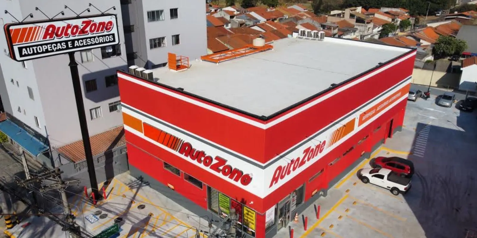 Vista aérea da loja AutoZone Guarulhos concluída, com fachada vermelha e totem da marca